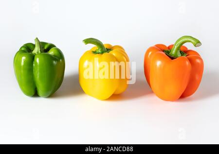 Poivrons de couleur sur fond blanc. Vert, jaune, orange poivre. Concept alimentaire. Les légumes frais mûrs. Vue de côté. Banque D'Images