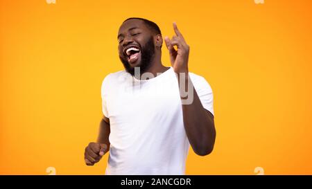 Heureux homme noir détendue contre danse fond jaune, s'amusant sur partie Banque D'Images