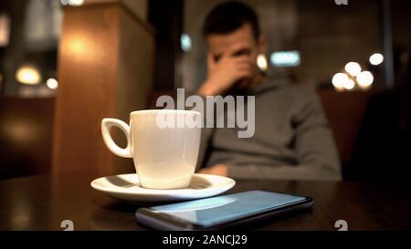 Sad man sitting in cafe, face de clôture, message de petite amie à propos de break up Banque D'Images