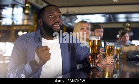 Anxieux d'amis de l'équipe multiraciale acclamant holding beer glasses, espoir de réussite Banque D'Images