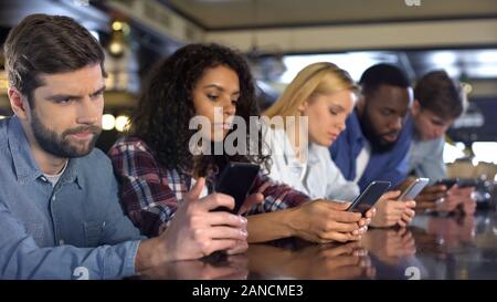 Défilement d'amis multi-raciale en ignorant les autres smartphones, gadget addiction Banque D'Images