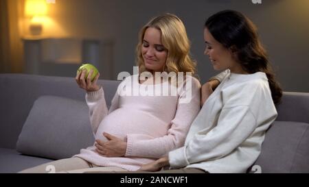 Pregnant woman holding apple parler avec un ami sur l'alimentation pour la santé de bébé Banque D'Images