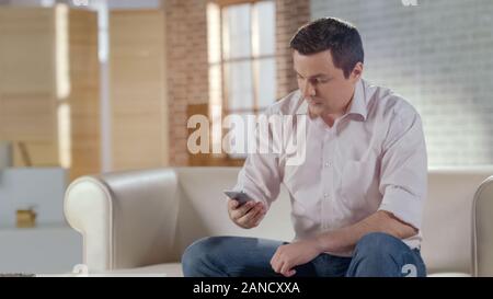 Jeune homme nombre de composition ou de lecture de message Business Partner sur le téléphone Banque D'Images