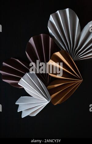 Coeurs en origami de papier de couleur neutre sur fond noir Banque D'Images