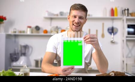 Handsome man holding tablet avec l'écran vert, application des cours de cuisine Banque D'Images