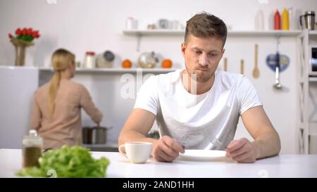 Homme affamé attend avec impatience le dîner, épouse la cuisson à la famine, l'arrière-plan Banque D'Images