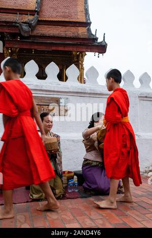 Les moines et les touristes participent à sai bat (matin l"aumône), Luang Prabang, Laos. Banque D'Images