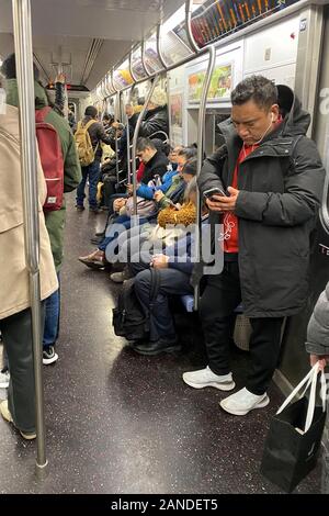 Les gens sont constamment sur leurs téléphones cellulaires lors de l'équitation les wagons du métro de New York City Banque D'Images