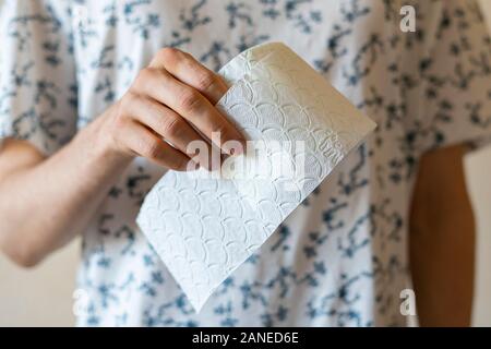 Une personne titulaire d'un rouleau de papier toilette blanc, debout sur le mur, de l'hygiène personnelle, isolée Banque D'Images