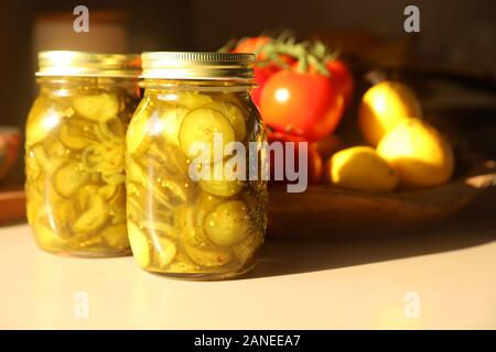 Profondeur de champ à un style de vie encore composition de deux bocaux scellés non ouvert de concombre cornichons faits maison fraîchement préparés. Objets banc cuisine Banque D'Images