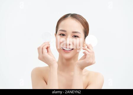 Femme souriante est titulaire de coton sur fond blanc. Concept de soins de la peau. Banque D'Images