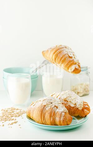 Flying roissants avec flocons d'amandes, le sucre en poudre et le lait biologique. Petit déjeuner d'un concept de lévitation. La verticale Banque D'Images