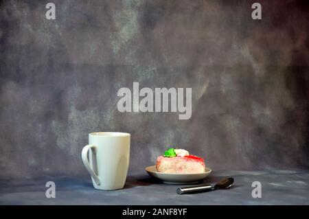 Tasse en céramique blanche de haute avec plateau et une soucoupe d'un biscuit gâteau avec la crème des protéines sur un fond gris. Close-up. Banque D'Images