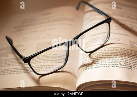 Paire de lunettes de lecture sur un livre ouvert, avec de belles ombres tombent sur les mots. Banque D'Images