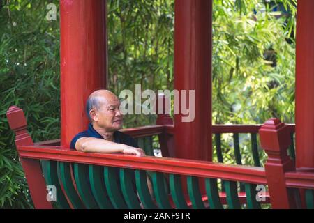 Chongqing, Chine - Août 2019 : retraite vieux homme asiatique chinois assis dans une tonnelle en parc en été Banque D'Images