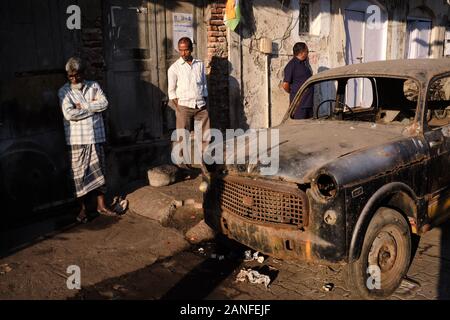 Une vieille voiture abandonnée et naufraie est restée sur une voie près des quais de Sassoon à Colaba, Mumbai, Inde Banque D'Images