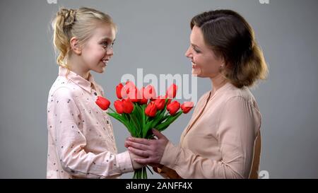 Fille donnant des fleurs à sa mère, le jour de womans félicitations, cadeau surprise Banque D'Images