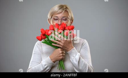 Hauts femme fleurs odorantes et souriant sur appareil photo, cadeau romantique, la féminité Banque D'Images