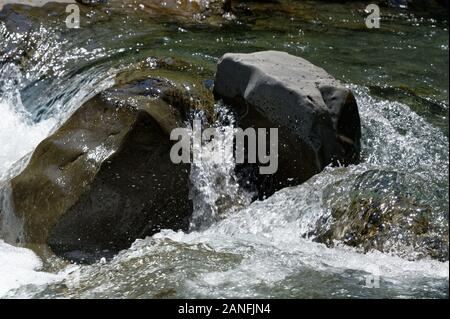 L'eau rapide fonctionne sur et autour d'un gros rocher dans une rivière Banque D'Images