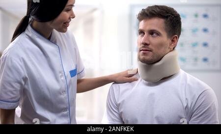 Smiling nurse man collier cervical mousse en soins médicaux, clinique, Banque D'Images