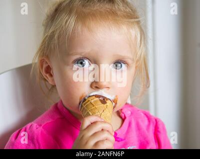 Petite fille avec ses yeux bleus et aux cheveux blonds eating ice cream Banque D'Images