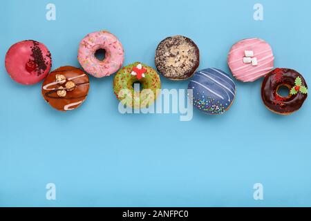 Sweet donuts colorés sur fond bleu, présenté sous la forme de diverses geomitric figure, flèche, carré, ligne, triangle, vue d'en haut. Desserts, jeu o Banque D'Images