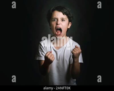 Angry boy sur fond noir Banque D'Images