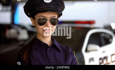 Friendly policier dans les lunettes à la caméra et au sourire, en service Banque D'Images