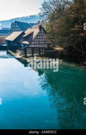 Allemagne, tôt le matin, le brouillard en mouvement sur la surface de l'eau pot bleu ou de l'allemand blautopf de blaubeuren forêt, un brillant bleu source naturelle dans la lumière du soleil chaude Banque D'Images