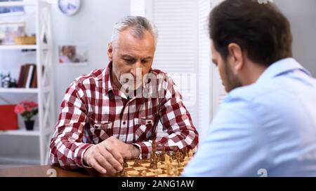Senior homme sérieux jouant aux échecs avec adversaire, compliqué la concurrence, sport Banque D'Images