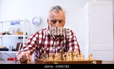 Vieil homme concentré en jouant aux échecs seulement, la préparation pour la compétition, la stratégie Banque D'Images