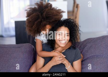 Little Black girl hug smiling maman sur la table de derrière Banque D'Images