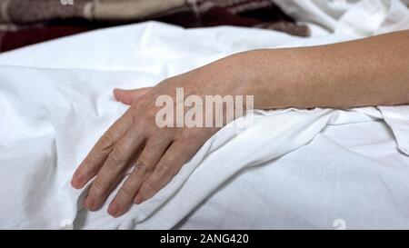 Femme de la haute main sur le linge de lit, couché dans lit de malade, souffrant de maladie, risque décès Banque D'Images