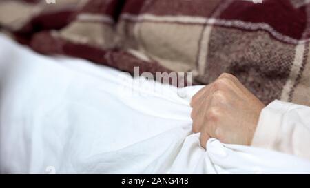Hauts femme souffrant de douleur vive et soudaine, serrant les draps, crampes Banque D'Images