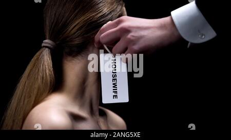 Mettre la main homme femme au foyer étiquette sur l'oreille des femmes, indiquant la place des femmes Banque D'Images