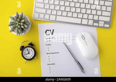 CV avec réveil, clavier de l'ordinateur, stylo sur fond jaune, vue du dessus Banque D'Images