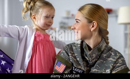 Enfant mignon avec nous à la recherche du pavillon de la mère et de l'armée à sourire, la famille patriote Banque D'Images
