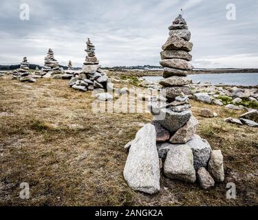 Plusieurs cheminées en pierre de granit (appelé cairns) sur le sentier du littoral en Bretagne, France, un jour nuageux. Banque D'Images