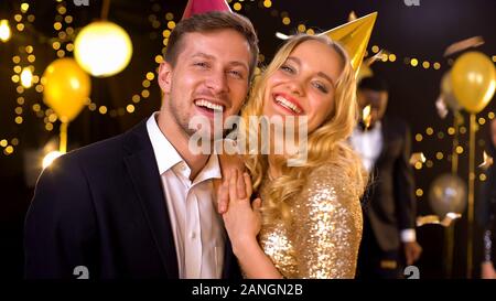 Heureux couple smiling on camera permanent, sous la chute des confettis à night club Banque D'Images