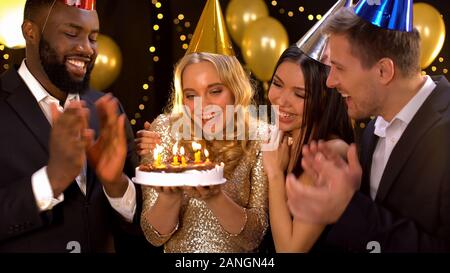 Société d'amis joyeux femme blonde félicitant sur anniversaire, holding cake Banque D'Images