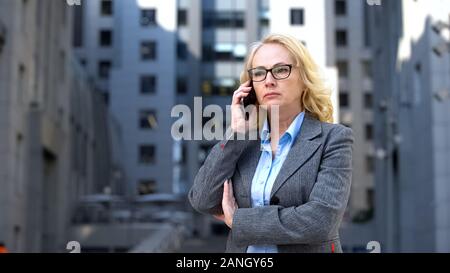 Senior female boss en colère et déçus de l'échec, parlant au téléphone Banque D'Images