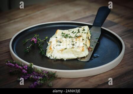 Recette végétarienne de halloumi au miel et thym sur une plaque avec un couteau Banque D'Images