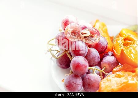 Un bouquet de rose avec des raisins mûrs un morceau de persimmon sur un fond uni. Copier l'espace. Banque D'Images