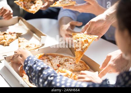 Close up d'employés ont briser dans office eating pizza à emporter de la livraison, les travailleurs heureux profiter de la nourriture italienne dégustation, passer le dîner ensemble, colle Banque D'Images