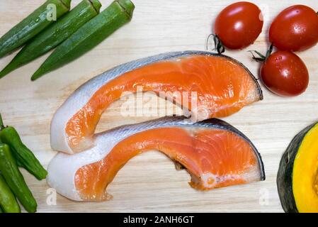 Le saumon orange coupe avec des légumes autour. Banque D'Images