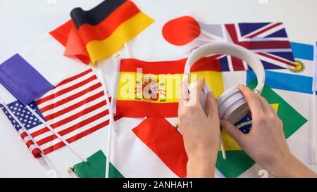 En prenant les mains du casque, différents pays les drapeaux sur la table, les leçons audio langue Banque D'Images