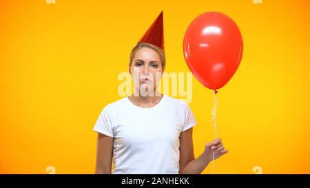 Contrarié femelle avec ballon rouge dans la main, le sentiment de solitude sur anniversaire, tristesse Banque D'Images