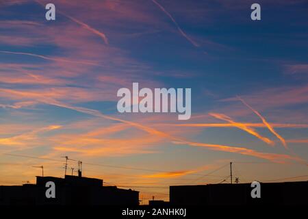 Des traces d'avions dans le ciel au coucher du soleil. Antennes de télévision sur les toits du bâtiment au coucher du soleil. Belle vue sur le coucher de soleil à partir de la fenêtre . Banque D'Images