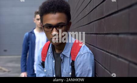 Intimidation african-american boy leaning against wall, peur de délinquant derrière Banque D'Images