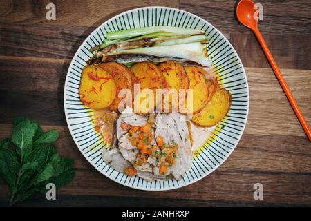 Agneau rôti avec pommes de terre au safran et poireaux. Vue sur le dessus / plat posé sur un fond en bois Banque D'Images